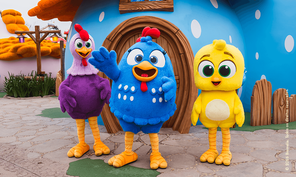 Galinha Pintadinha, Galo Carijó e Pintinho Amarelinho em frente à casinha azul da Vila da Galinha Pintadinha no Beto Carrero World